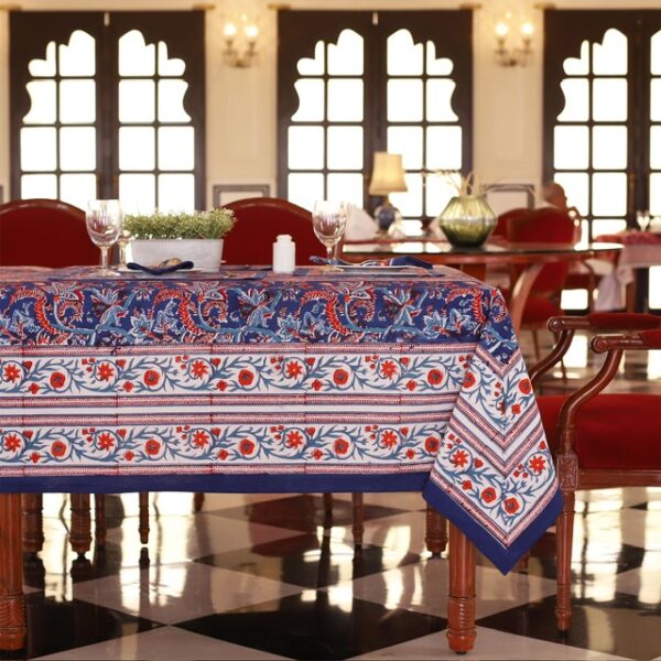 Nappe Mumbai Mirage bleu avec des motifs floraux abstraits en nuances de rouge et orange, évoquant une ambiance festive et luxueuse.