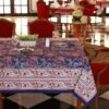 Nappe Mumbai Mirage bleu avec des motifs floraux abstraits en nuances de rouge et orange, évoquant une ambiance festive et luxueuse.