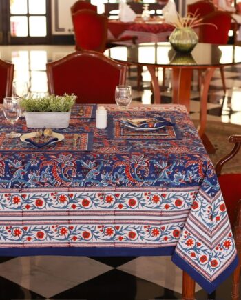 Nappe Mumbai Mirage bleu avec des motifs floraux abstraits en nuances de rouge et orange, évoquant une ambiance festive et luxueuse.