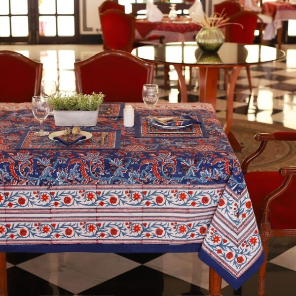 Nappe Mumbai Mirage bleu avec des motifs floraux abstraits en nuances de rouge et orange, évoquant une ambiance festive et luxueuse.