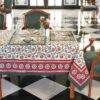 Nappe Rajasthan Royal en coton blanc avec motifs floraux rouges, jaunes et verts, imprimée à la main selon la technique du block print, posée sur une table élégante.