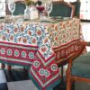 Nappe Rajasthan Royal en coton blanc avec motifs floraux rouges, jaunes et verts, imprimée à la main selon la technique du block print, posée sur une table élégante.