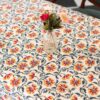 Nappe Rajasthan Royal en coton blanc avec motifs floraux rouges, jaunes et verts, imprimée à la main selon la technique du block print, posée sur une table élégante.