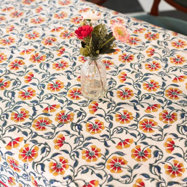 Nappe Rajasthan Royal en coton blanc avec motifs floraux rouges, jaunes et verts, imprimée à la main selon la technique du block print, posée sur une table élégante.