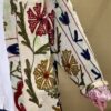 Détail du Manteau Long Meera - Khanta Suzani - Modèle Camille - Manteau de couleur blanc cassé, kaki, rouge et bleu marine fleurit