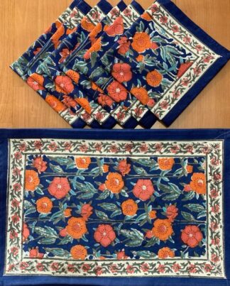 Sets de table Pashmina aux motifs floraux imprimés à la main, accompagnés de serviettes assorties en coton, dans des tons bleu et orangé, présentés à plat sur une surface blanche, illustrant un art de la table élégant, artisanal et inspiré de la tradition indienne du block-print.
