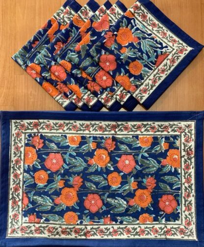 Sets de table Pashmina aux motifs floraux imprimés à la main, accompagnés de serviettes assorties en coton, dans des tons bleu et orangé, présentés à plat sur une surface blanche, illustrant un art de la table élégant, artisanal et inspiré de la tradition indienne du block-print.