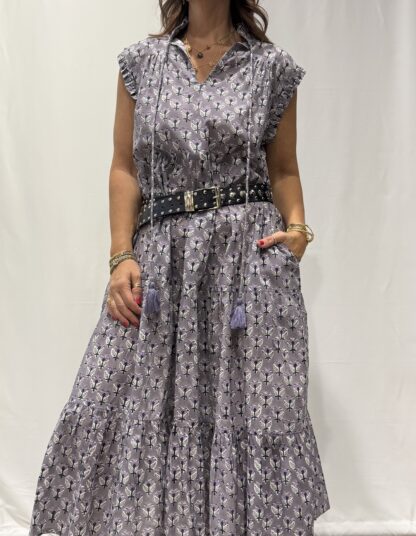 Robe Chandra Mauve - Femme portant une robe longue sans manches à imprimé floral, avec volants et liens à pompons, coupe ample et col tunisien.