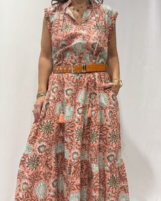 Robe Chandra Rose - Femme portant une robe longue sans manches à imprimé floral, avec volants et liens à pompons, coupe ample et col tunisien.