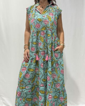 Robe Chandra Turquoise - Femme portant une robe longue sans manches à imprimé floral, avec volants et liens à pompons, coupe ample et col tunisien.