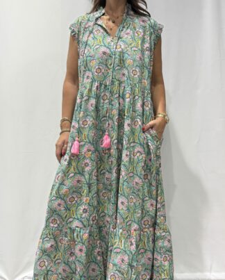 Robe Chandra Verte Fleurie - Femme portant une robe longue sans manches à imprimé floral, avec volants et liens à pompons, coupe ample et col tunisien.