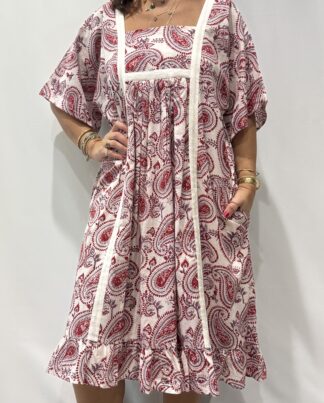 Robe Mallika blanche framboise : Femme portant une robe blanche à imprimé floral rouge framboise et mauve avec empiècements contrastés blanc et manches courtes amples.