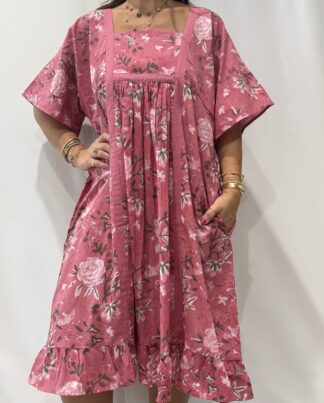 Robe Mallika Rose : Femme portant une robe à imprimé floral rose et vert, avec empiècements contrastés jaunes et manches courtes amples.
