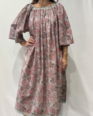 Robe Sita Grise -Femme portant une robe ample en coton grise et rose à imprimé floral, manches larges et col smocké en dentelle