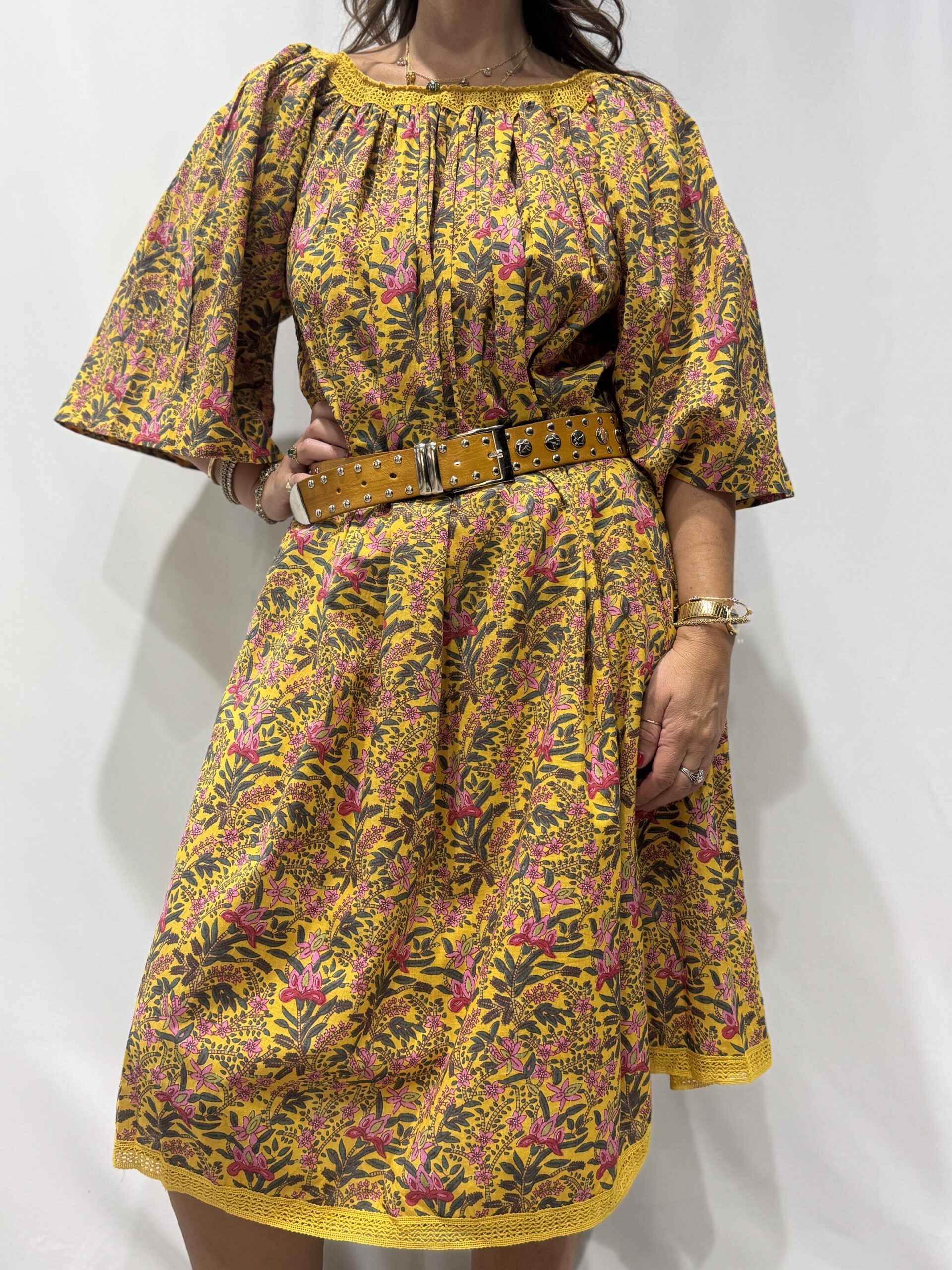 Robe Sita Jaune Fleurie -Femme portant une robe ample en coton jaune fleurie à imprimé floral, manches larges et col smocké en dentelle