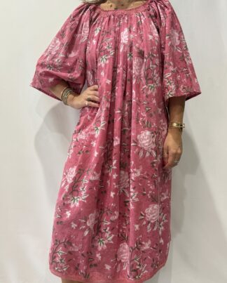Robe Sita Rose -Femme portant une robe ample en coton rose à imprimé floral, manches larges et col smocké en dentelle