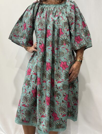 Robe Sita Verte Rose -Femme portant une robe ample en coton vert et rose à imprimé floral, manches larges et col smocké en dentelle