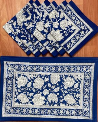 Sets de table Bollywood aux motifs floraux imprimés à la main, accompagnés de serviettes assorties en coton, dans des tons bleus, présentés à plat sur une surface blanche, illustrant un art de la table élégant, artisanal et inspiré de la tradition indienne du block-print.