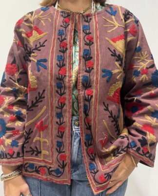 Veste Isha de Micasasté pour femme, brodée aux motifs floraux colorés rouges, bleus, dorés et noirs sur fond vieux rose, coupe droite et manches longues.