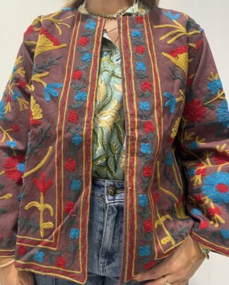 Veste Jaya de Micasasté pour femme, brodée, fond vieux rose et marron chaud, ornée de motifs floraux jaunes, rouges et bleu clair, coupe droite et manches longues.