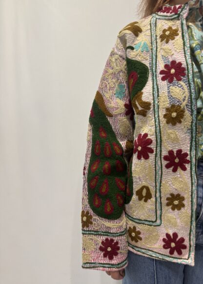 Veste Kiara de Micasasté pour femme, brodée de fleurs bordeau et kaki clair et de paons vert foncé, bordeau et kaki sur fond rose pâle.