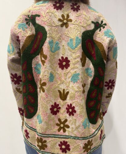 Veste Kiara de Micasasté pour femme, brodée de fleurs bordeau et kaki clair et de paons vert foncé, bordeau et kaki sur fond rose pâle.