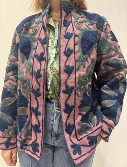 Veste Lalita de Micasasté pour femme, brodée, fond vieux rose, ornée de motifs végétaux bleu foncé, vert et violet, coupe droite et manches longues.
