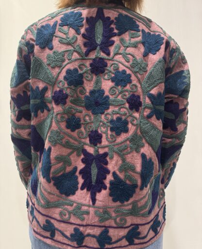 Veste Lalita de Micasasté pour femme, brodée, fond vieux rose, ornée de motifs végétaux bleu foncé, vert et violet, coupe droite et manches longues.