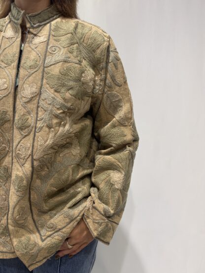 Veste Mahima de Micasasté pour femme, brodée sur base beige avec des motifs en relief dans des tons de vert doux et sable, coupe droite et col montant.