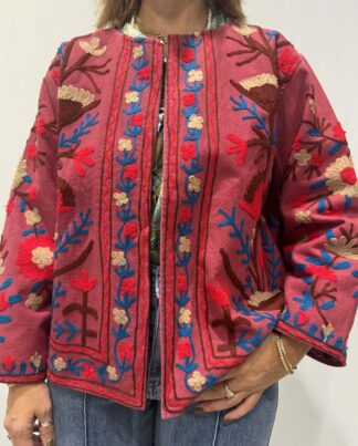 Veste Priya Micasasté portée de face, rouge foncé avec broderies florales en bordeaux, rouge vif, beige et bleu. Veste Courte, manches longue et col mao.