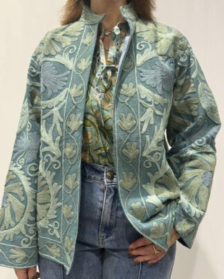 Veste Shanti de Micasasté portée de face, une veste courte bleu à col mao et manches longues, broderies en bleu pâle et bleu gris.