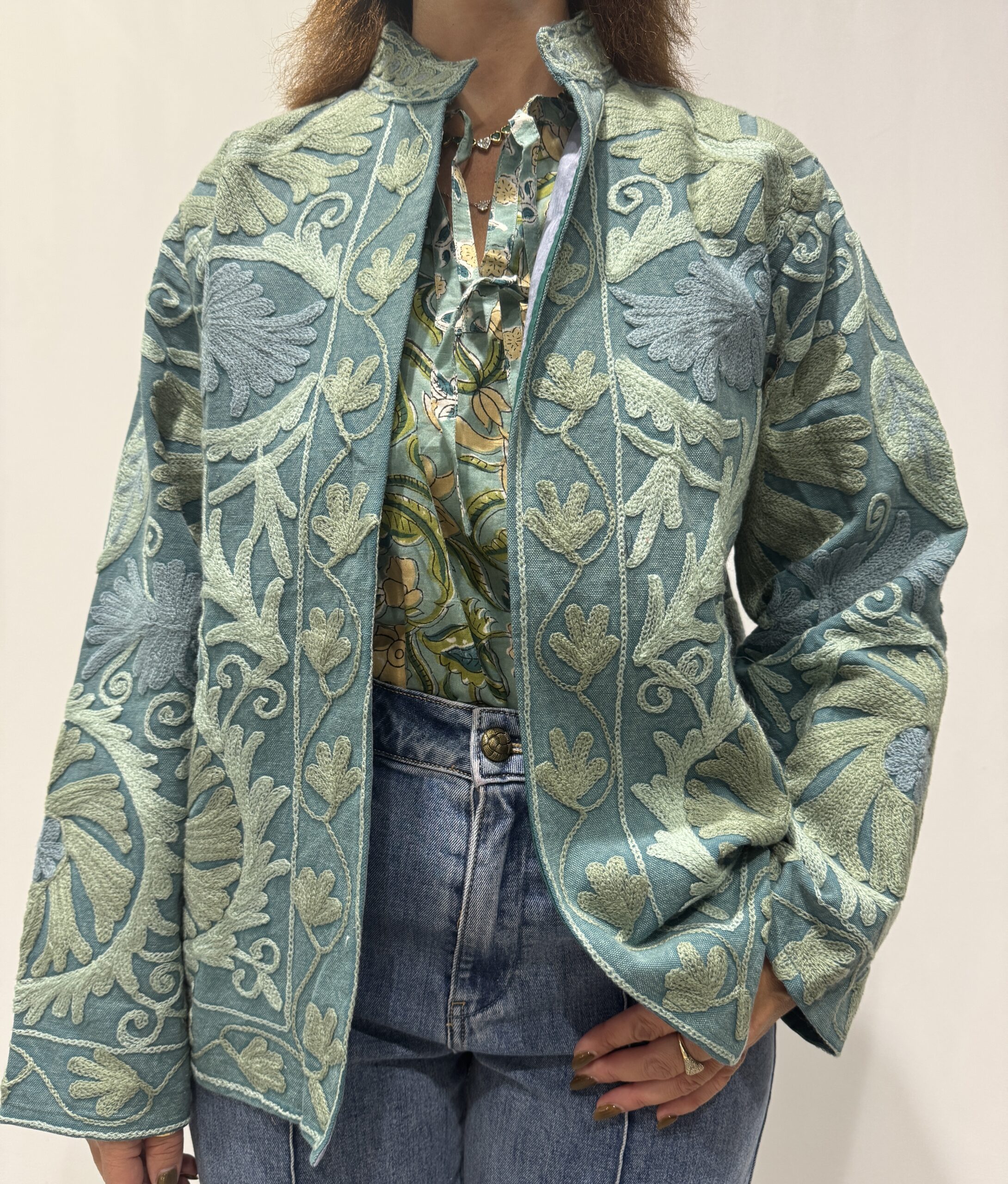 Veste Shanti de Micasasté portée de face, une veste courte bleu à col mao et manches longues, broderies en bleu pâle et bleu gris.
