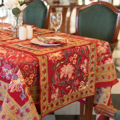 Nappe Maharani Glow rectangulaire 180x340, motifs floraux colorés sur fond rouge, décor de table élégant.
