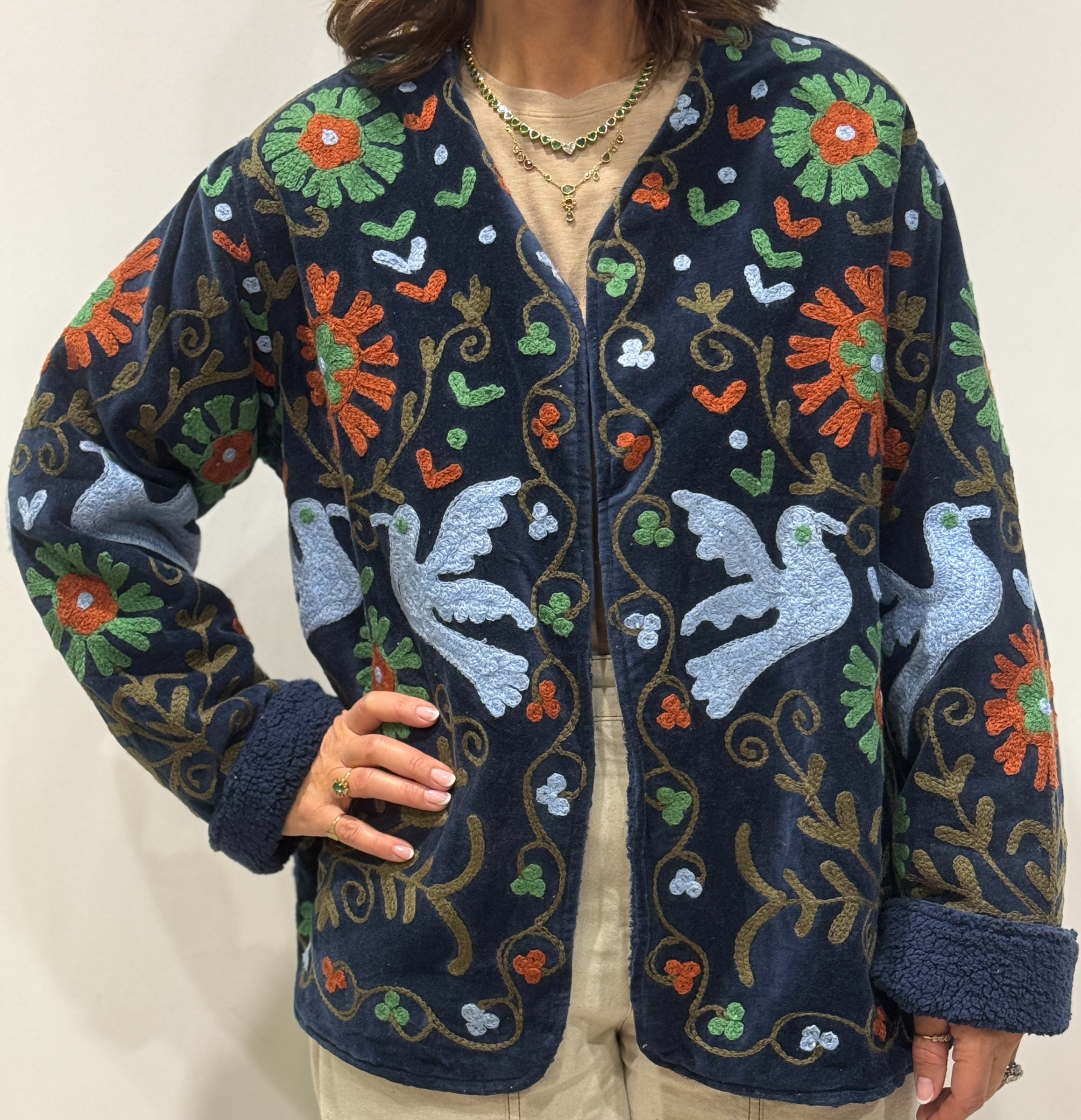 Femme portant la veste Eshna en velours bleu marine brodé à la main, avec motifs colorés et doublure bleu marine.