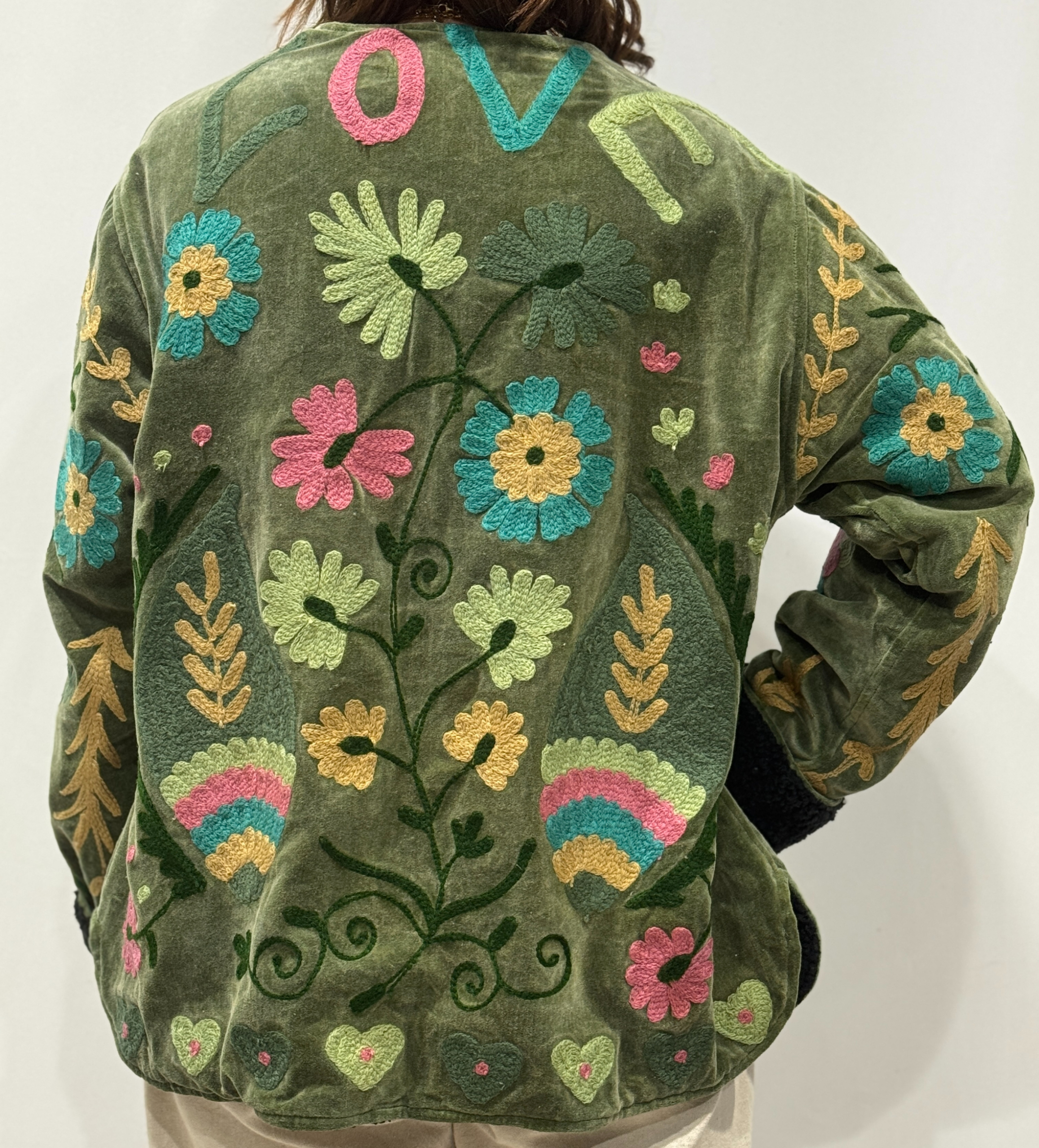 Détail du dos de la veste Indra, avec motifs floraux colorés et le mot “LOVE” brodé en haut.