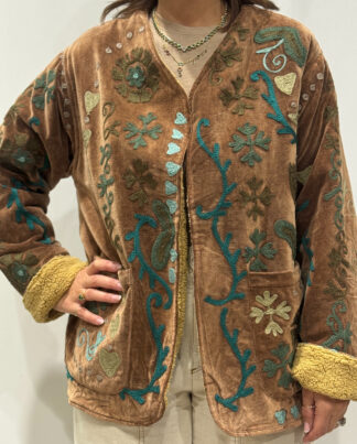 Femme portant la veste Kaira en velours marron brodé à la main, avec doublure beige et motifs floraux.