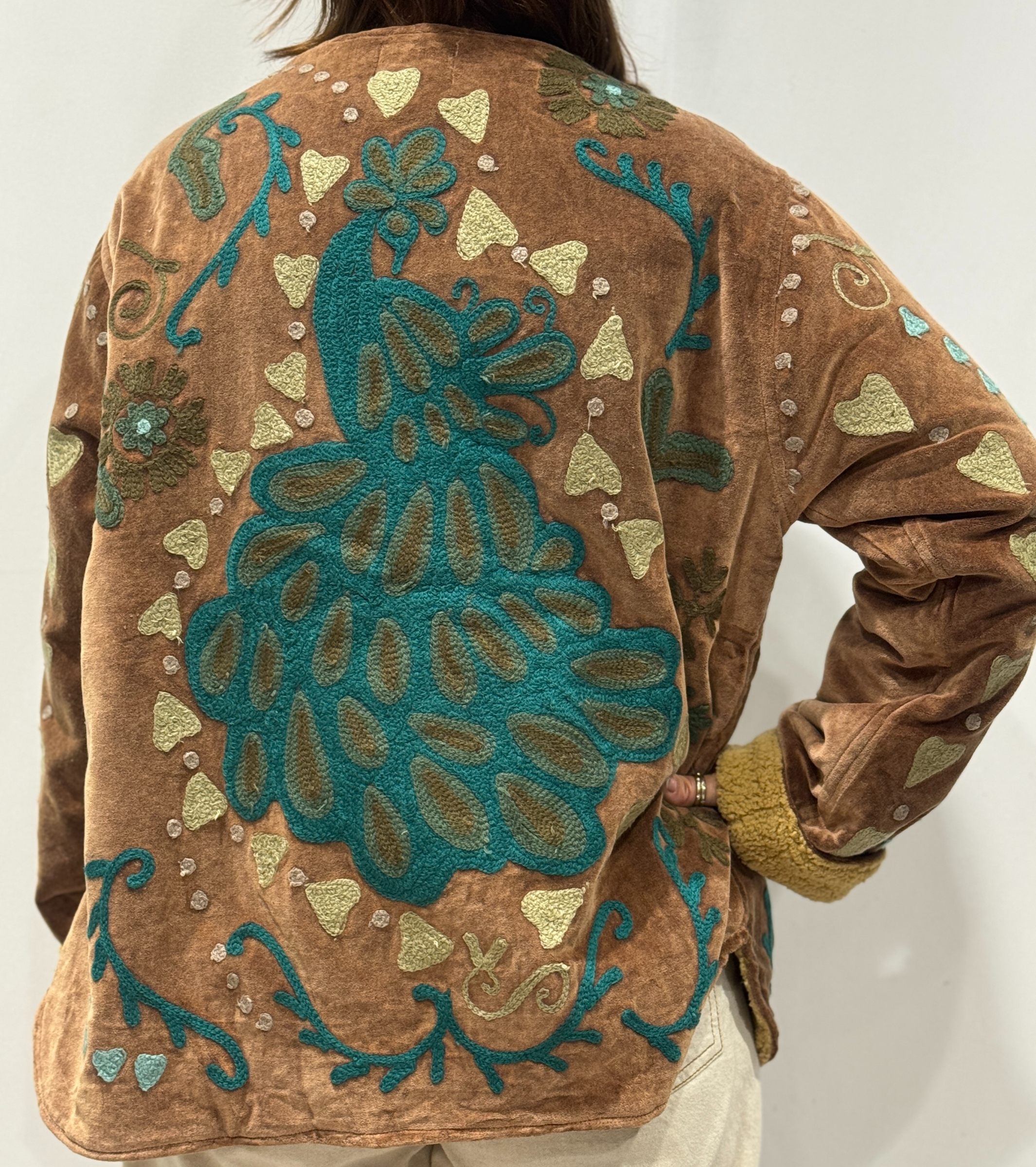 Détail du dos de la veste Kaira, avec paon brodé entouré de cœurs beige et motifs floraux.