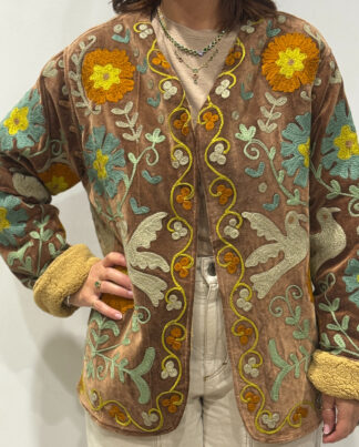 Femme portant la veste Luna en velours marron brodé à la main, avec doublure beige et motifs floraux.