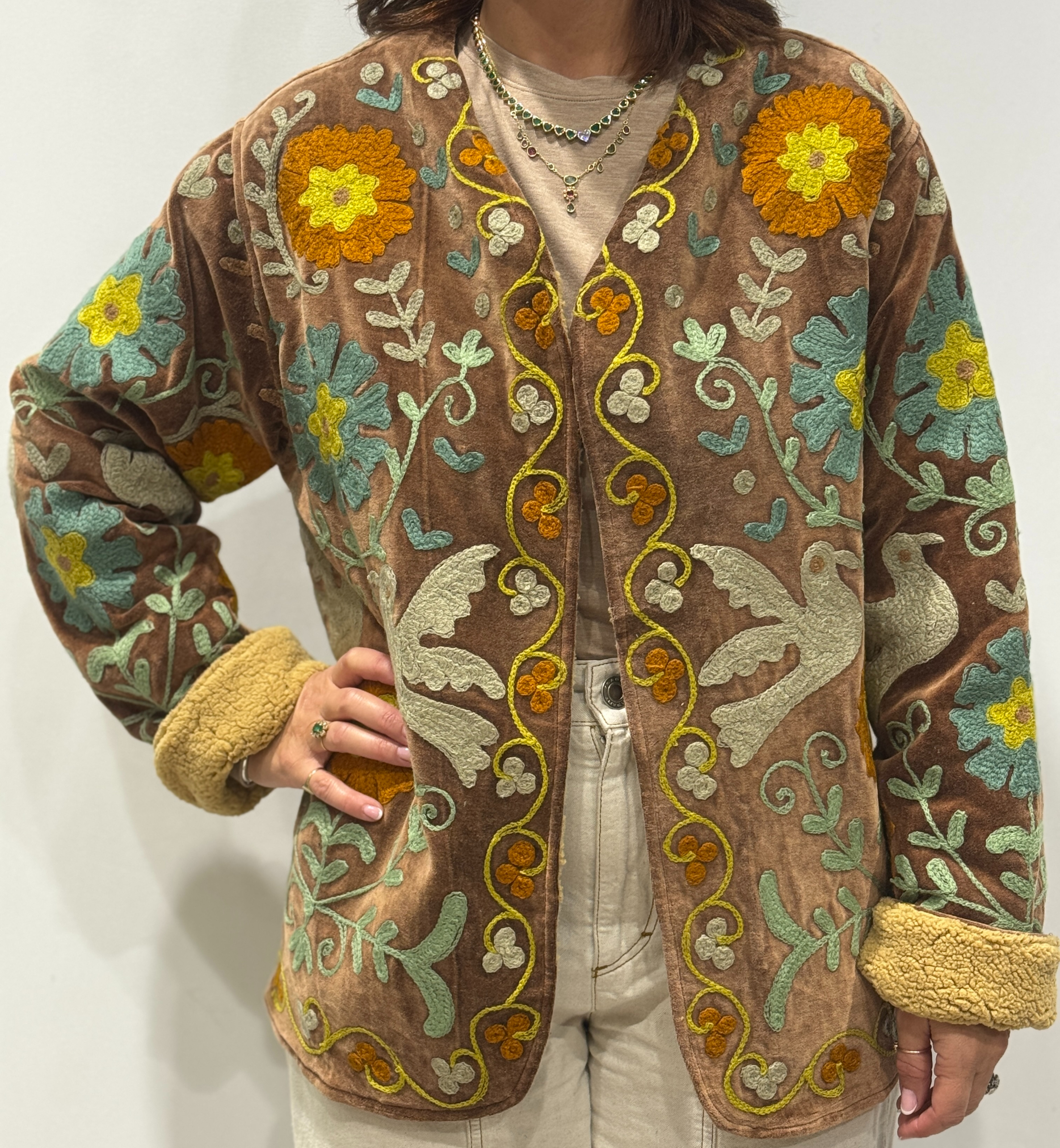 Femme portant la veste Luna en velours marron brodé à la main, avec doublure beige et motifs floraux.