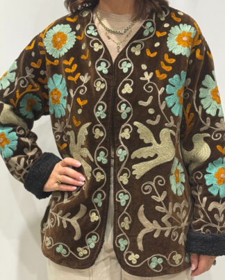 Stéphanie portant la veste Miraï en velours marron avec des broderies bleu clair, beige et orange