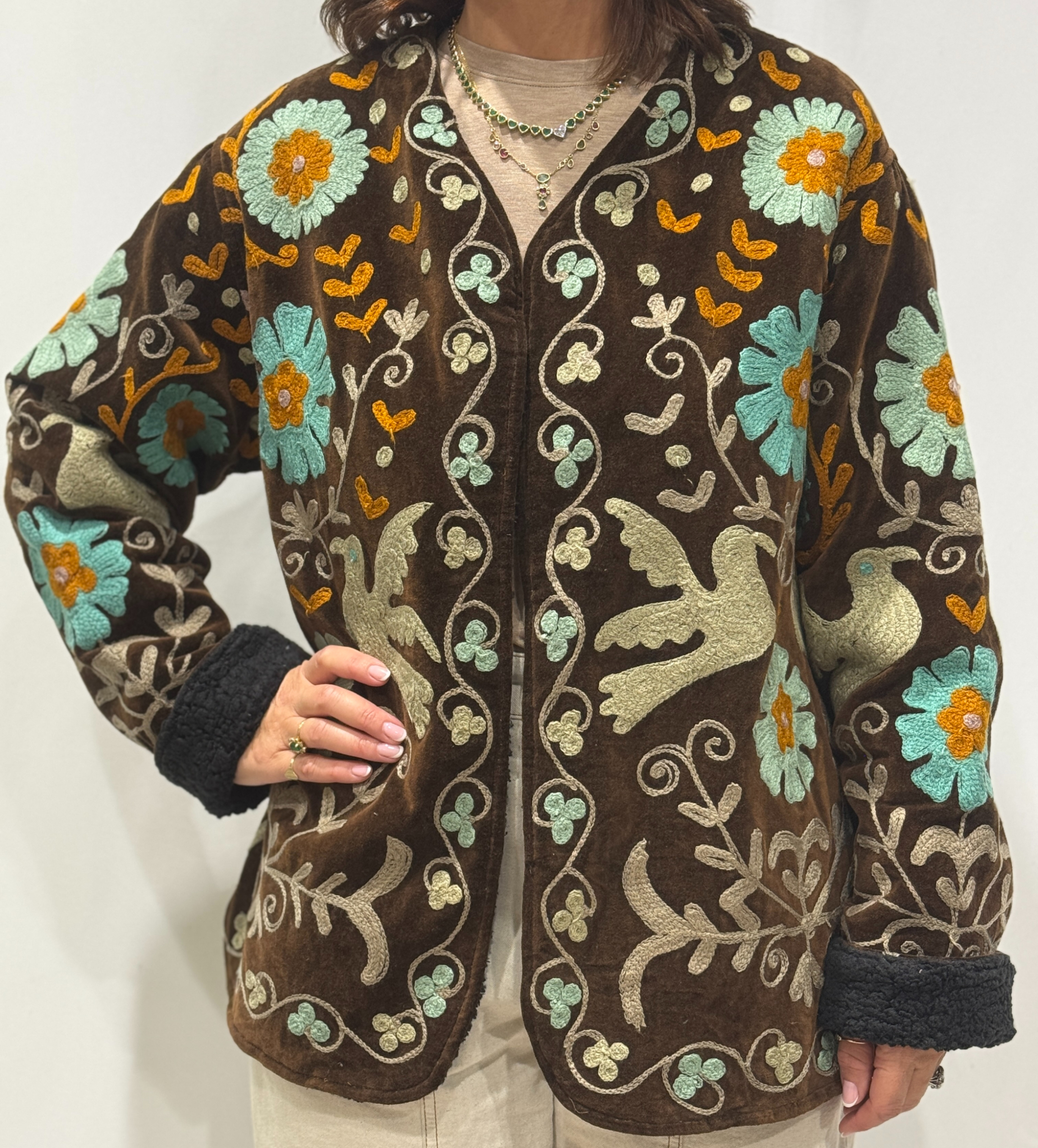 Stéphanie portant la veste Miraï en velours marron avec des broderies bleu clair, beige et orange