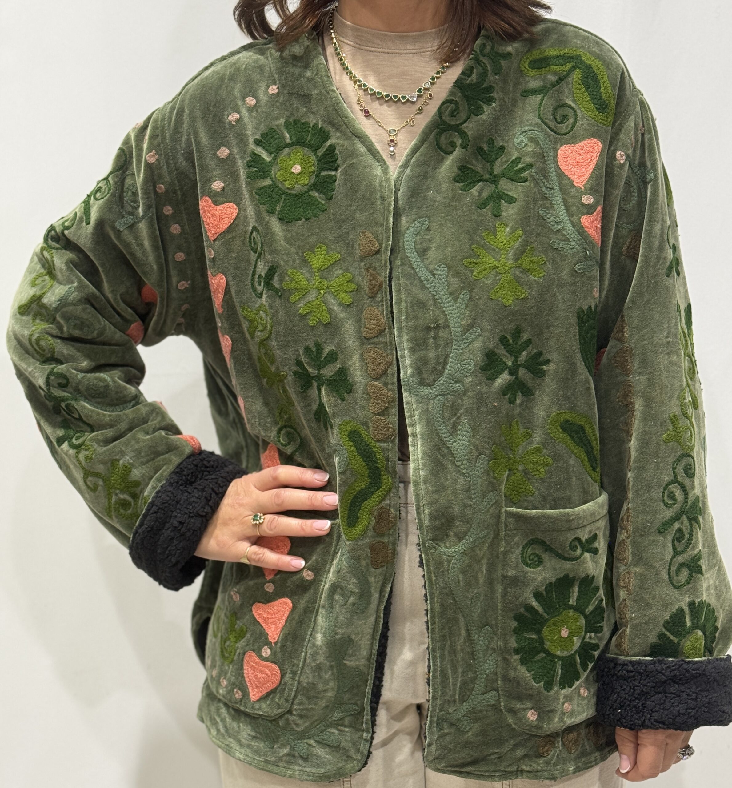 Stéphanie portant la veste Naya en velours kaki brodé à la main, col V et poches visibles.