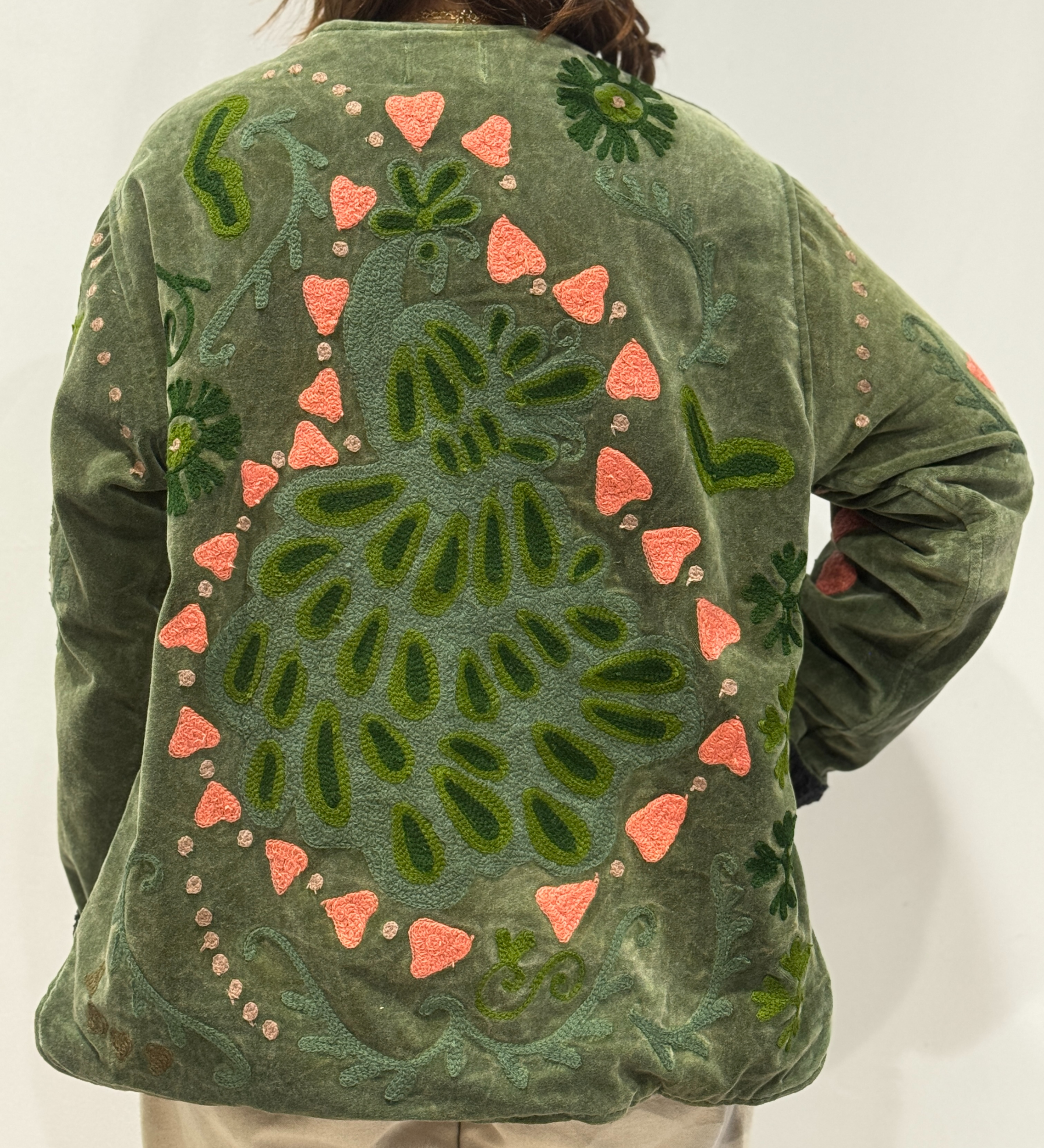 Détail du dos de la veste Naya, avec un paon brodé entouré de cœurs roses.