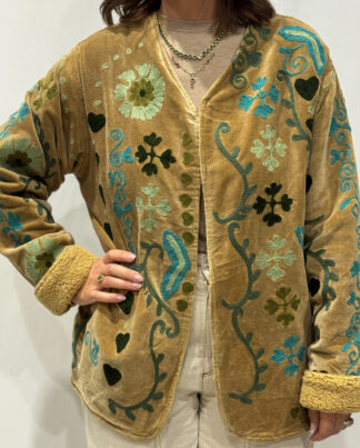 Stéphanie portant la veste Raya en velours beige brodé à la main, col V et intérieur fourré beige.