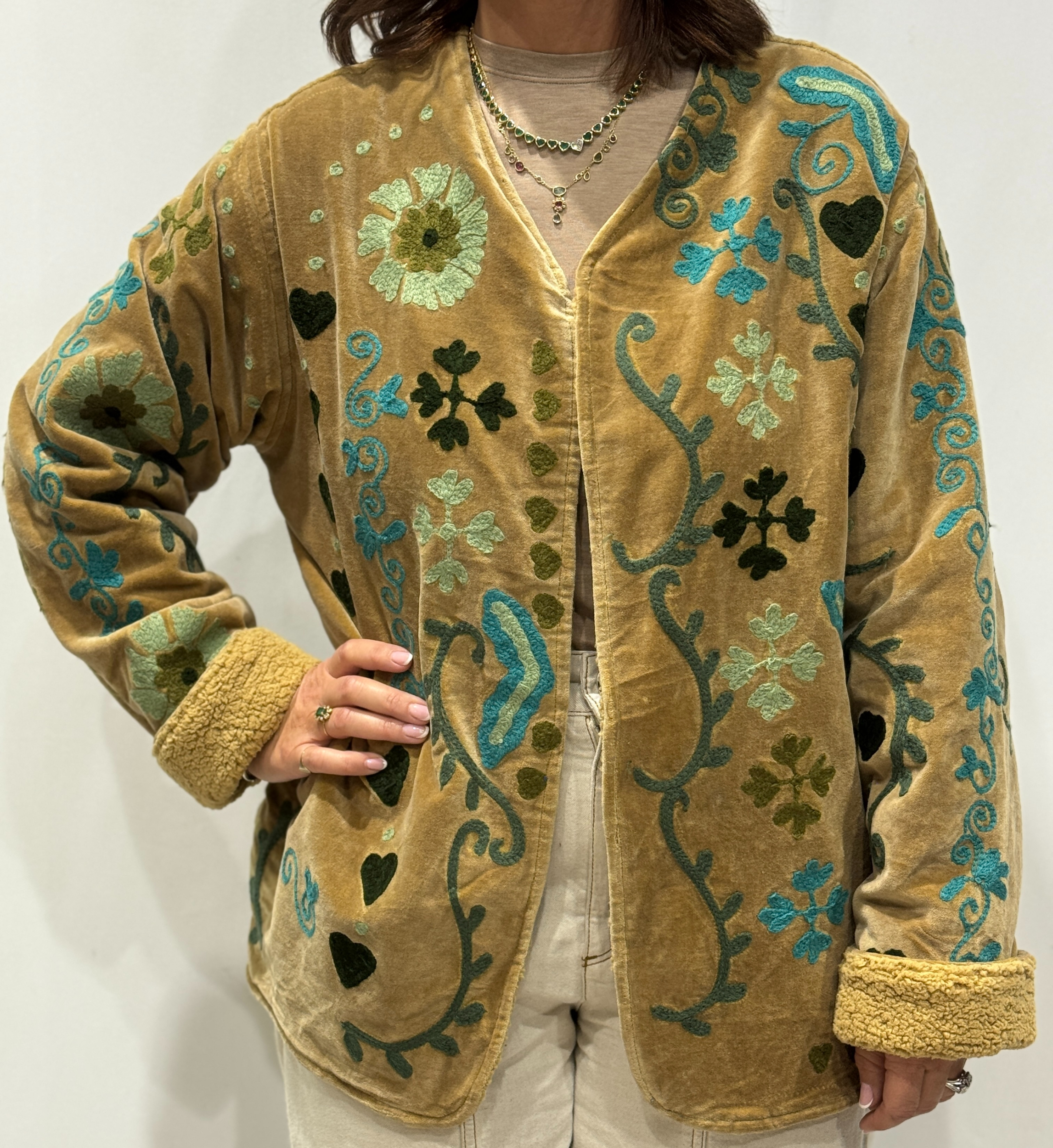 Stéphanie portant la veste Raya en velours beige brodé à la main, col V et intérieur fourré beige.