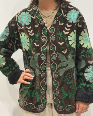 Femme portant la veste Sahra en velours marron foncé brodé à la main, avec doublure noire et motifs floraux.