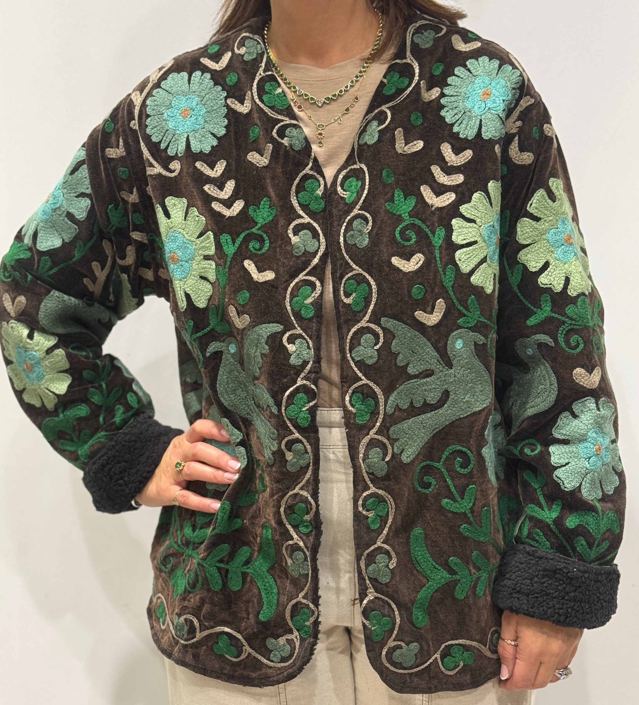 Femme portant la veste Sahra en velours marron foncé brodé à la main, avec doublure noire et motifs floraux.