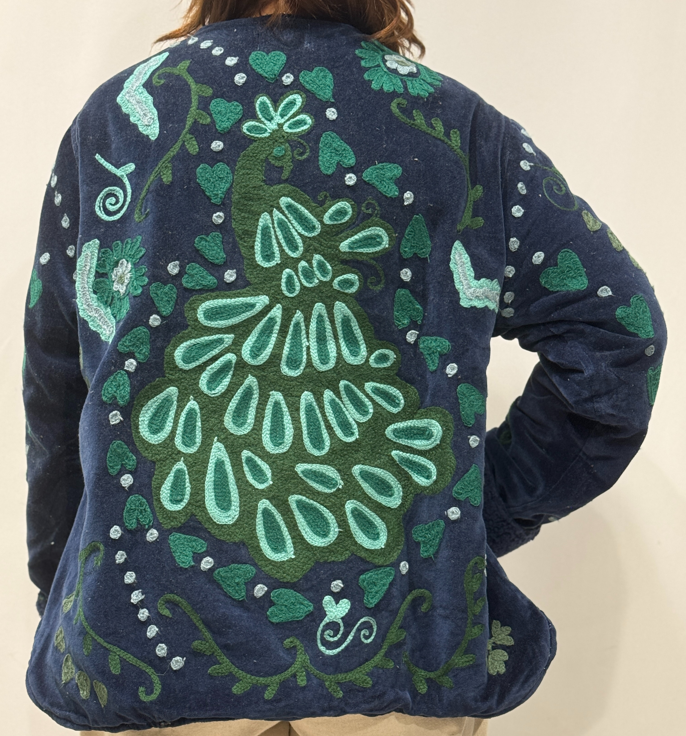 Détail du dos de la veste Sanaï, avec paon brodé entouré de cœurs vert foncé.