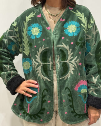 Femme portant la veste Tavira en velours vert foncé brodé à la main, avec doublure noire et motifs floraux.