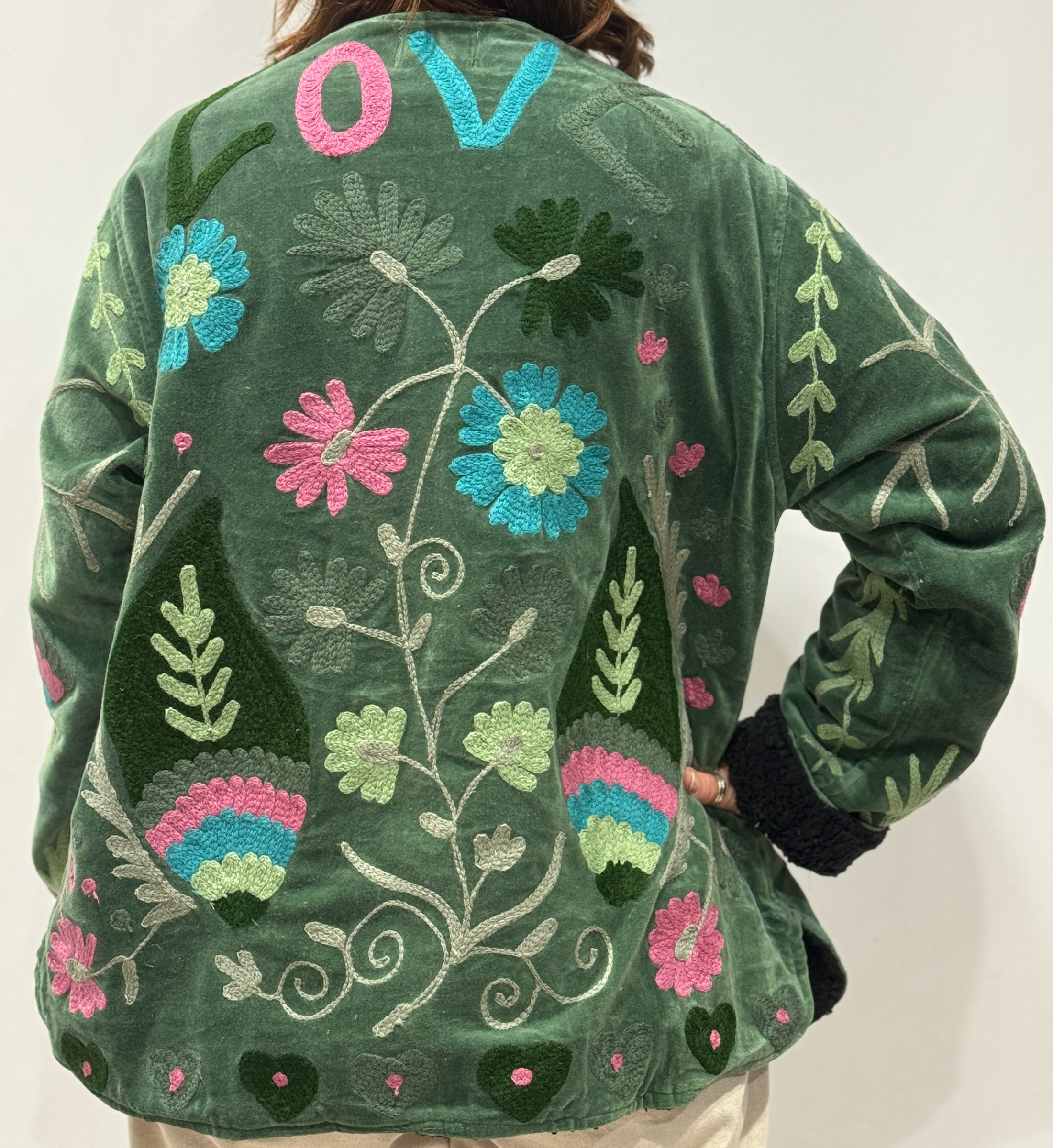 Détail du dos de la veste Tavira, avec motifs floraux colorés et le mot “LOVE” brodé en haut.